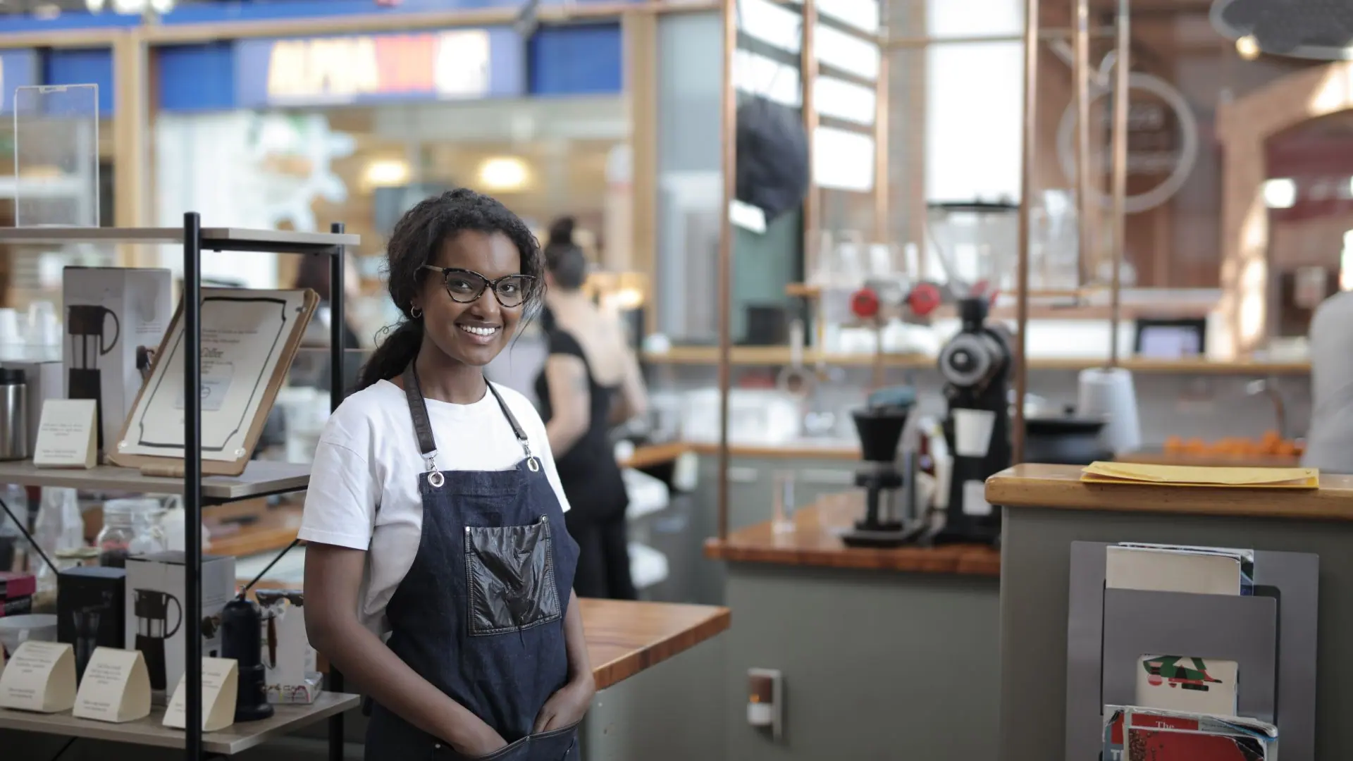 Dueña de una cafetería sonriendo detrás del mostrador