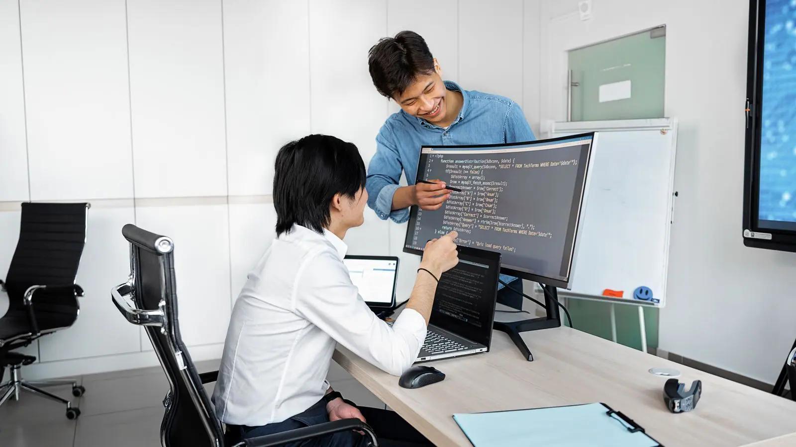 Dos desarrolladores revisando código en una pantalla